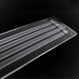 Image of the chip from above infront of a black background. This chip is translucent with four channels running along the horizontal axis of the chip.