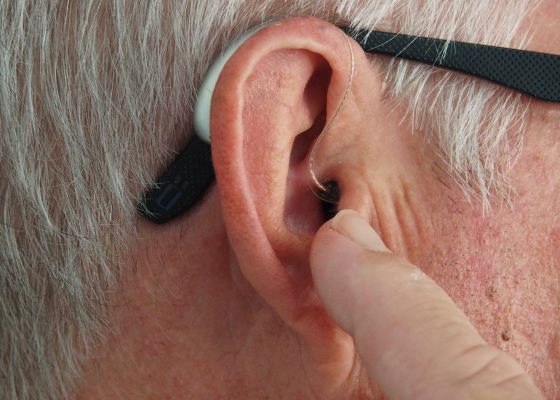 ear of an old man with technological device showing the importance of medical technology nd micropumps for health and care